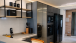 Prateleiras de madeira com estrutura metálica preta em cozinha planejada moderna com iluminação indireta.